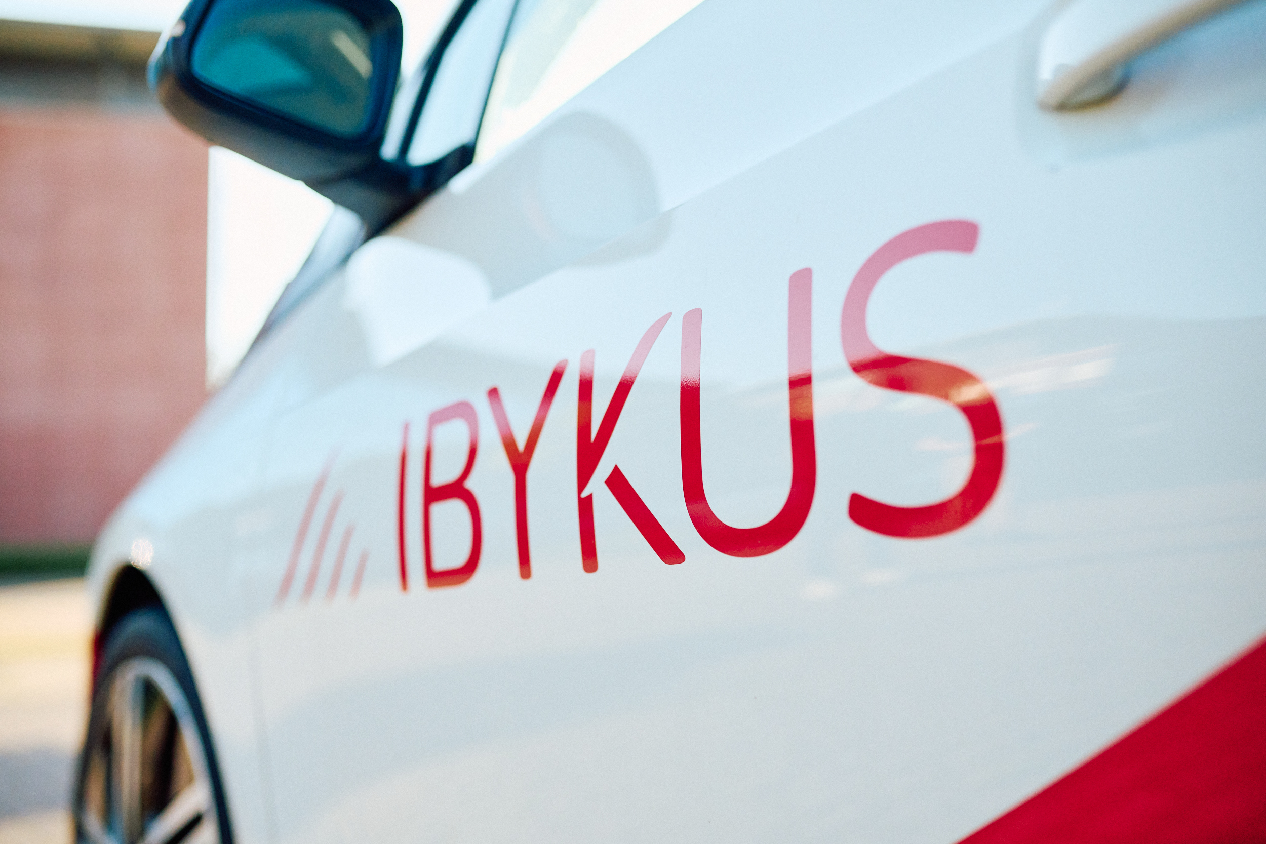 Ein Auto mit IBYKUS-Beklebung in rot und weiß mit dem Logo der IBYKUS AG